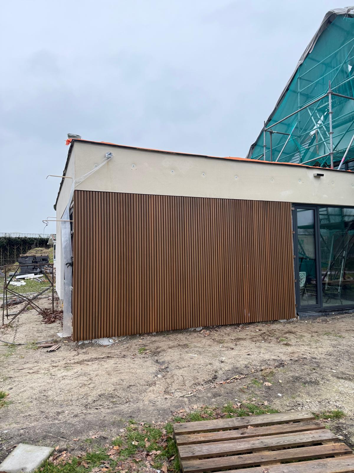 Verticale gevelbekleding langs een witte gevel