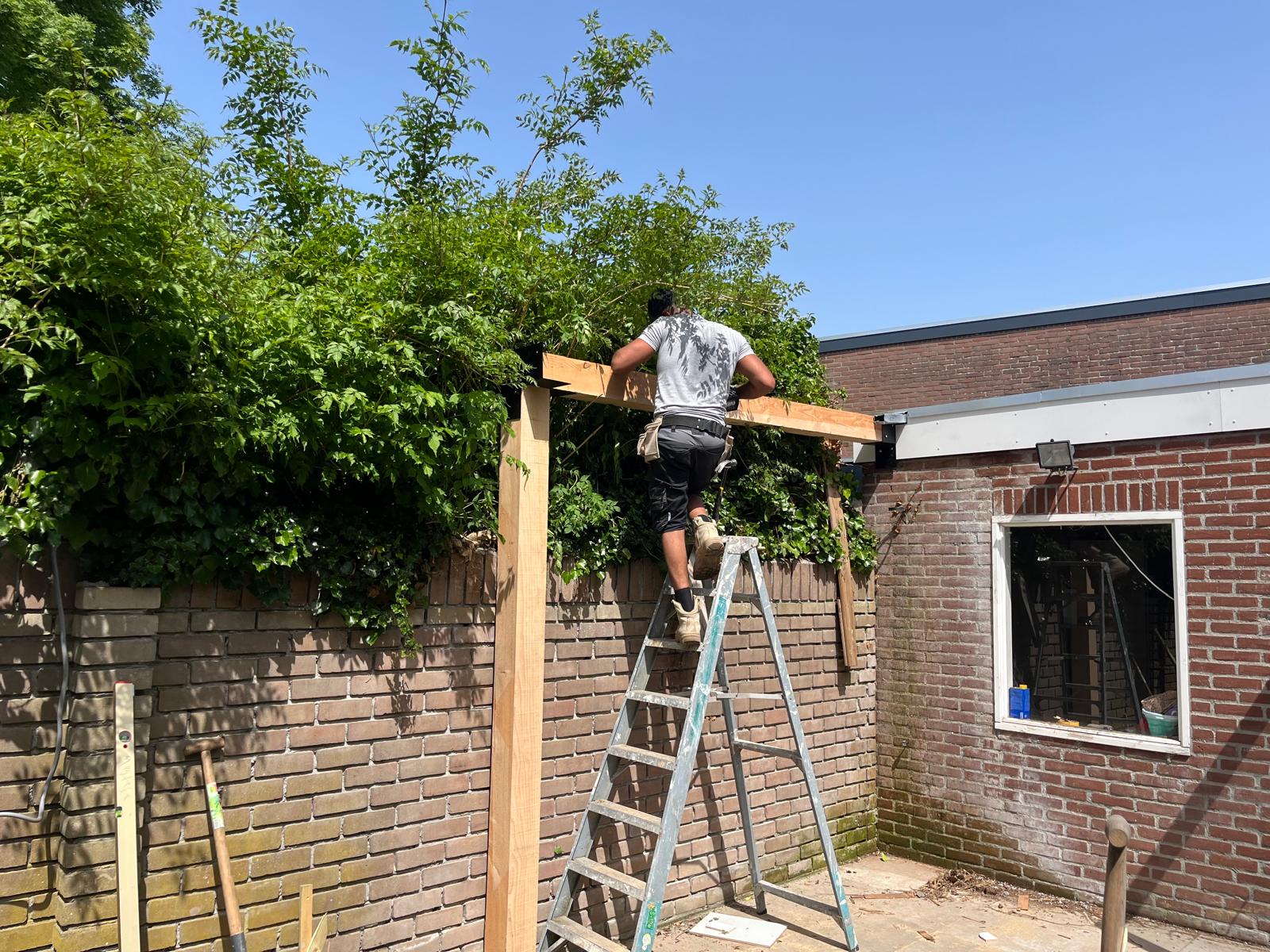 Mustafa Albaas tijdens bouw van houten pergola